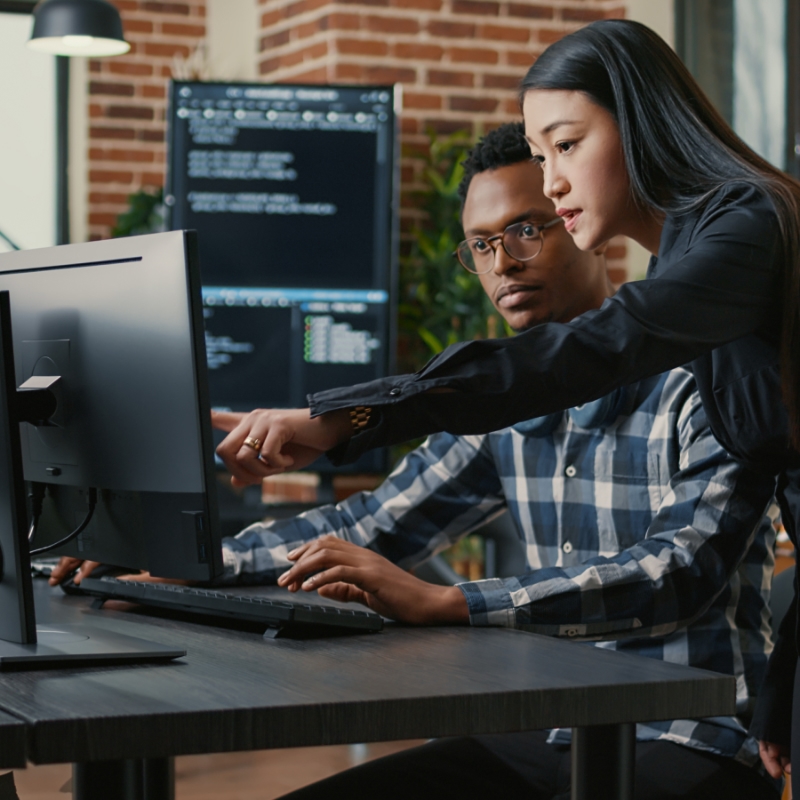 Student workers discussing technology while paying attention to a computer monitor.